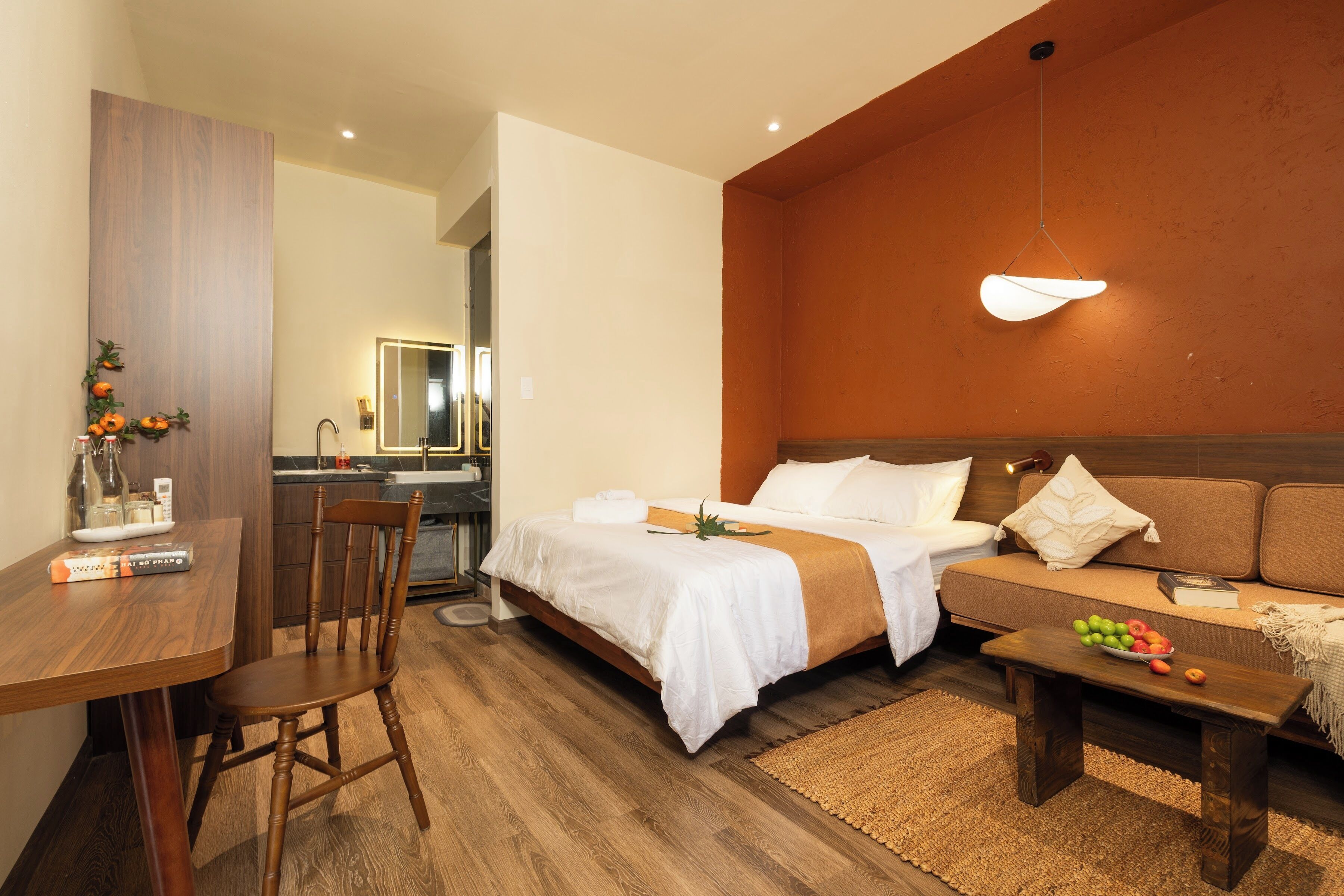 A hotel room with a bed, a sofa, a dining table, and a chair.