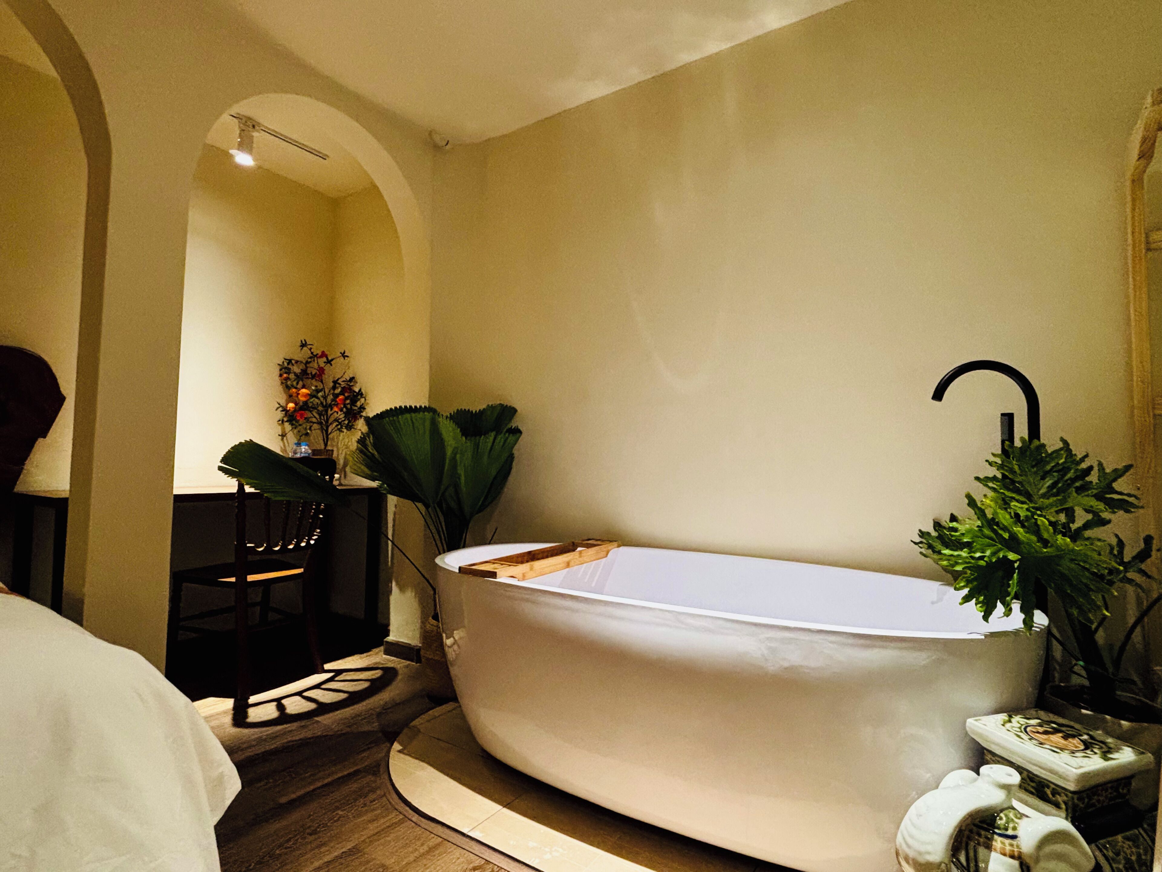 A modern bathroom with a freestanding bathtub, a small sink, and a mirror.