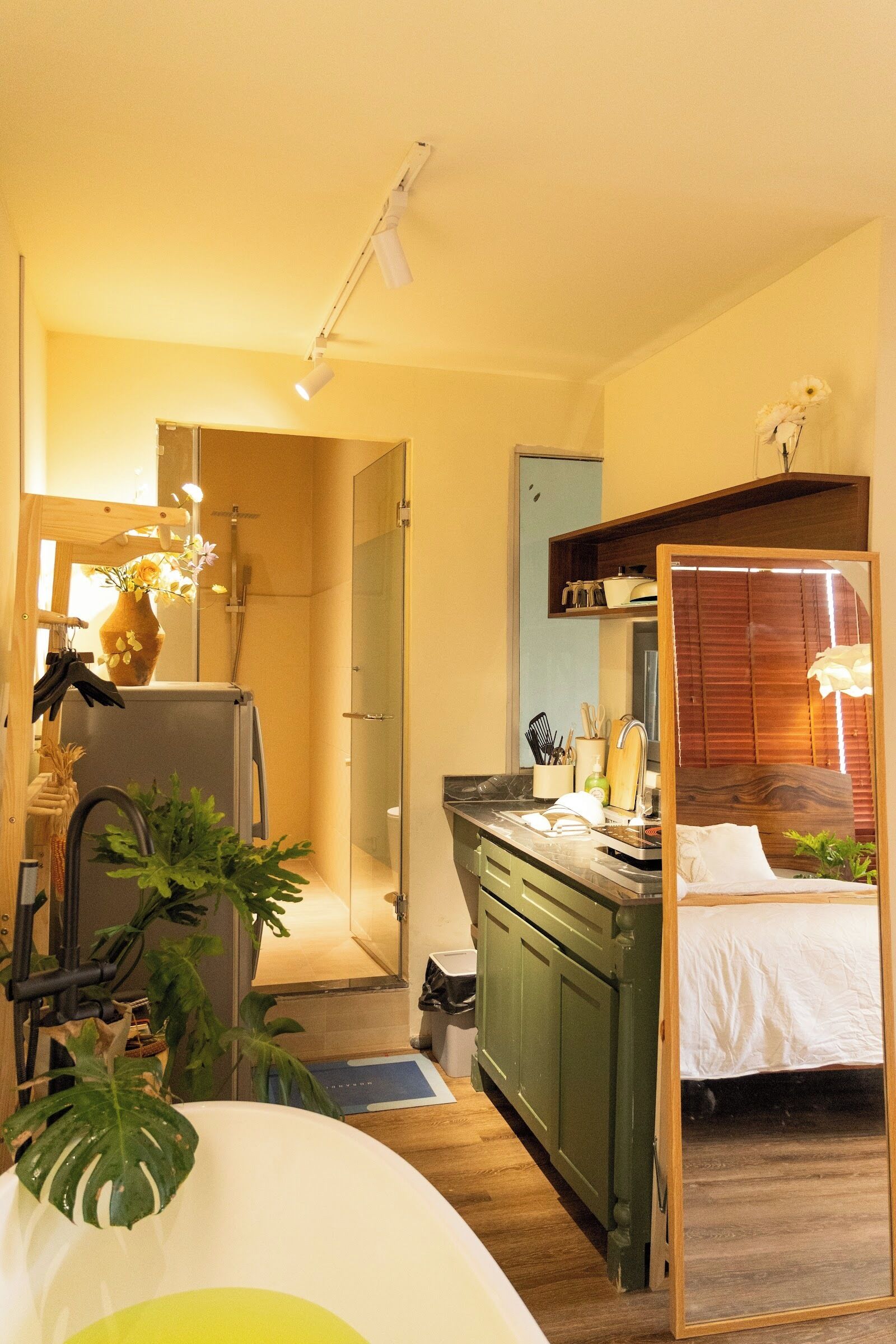 Una habitación pequeña con cama, espejo, lavamanos y ducha.