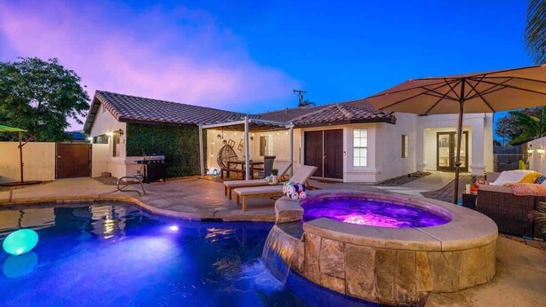 A swimming pool with a hot tub, lounge chairs, and a covered patio area. - Relaxing 4BR Retreat w/ Refreshing Pool (Bermuda Dunes)