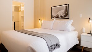 A neatly made bed with a grey throw blanket, a framed abstract artwork on the wall, and a bedside lamp. - w Charming 2BR Stay in Miraflores (Lima)
