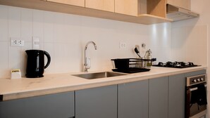 A modern kitchen with grey cabinets, a stainless steel sink, a black coffee maker, and a gas stove. - w Charming 2BR Stay in Miraflores (Lima)