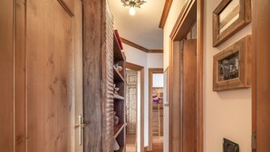 A wooden hallway with a built-in bookshelf, a door with a brass handle, and a light fixture on the ceiling.