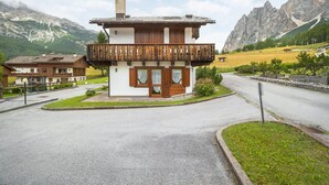 A chalet-style building with a wooden balcony, surrounded by a mountainous landscape.
