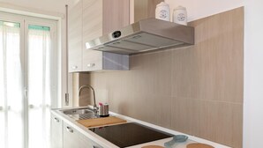 A modern kitchen with a built-in stove, a stainless steel range hood, and a window with curtains. - Superior Apartment with Balcony (ROMA)