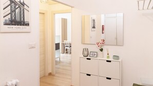 A hallway with a white cabinet, a mirror, and a framed picture of the New York City bridge. - Superior Apartment with Balcony (ROMA)