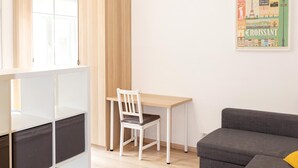 A modern room with a wooden floor, a white desk, a grey sofa, and a white shelving unit. - Superior Apartment with Balcony (ROMA)
