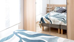 A bedroom with a bed, a wardrobe, and a window with a leaf pattern. - Superior Apartment with Balcony (ROMA)