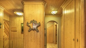 A wooden hallway with a central column, a mirror, and a door with a keyhole.