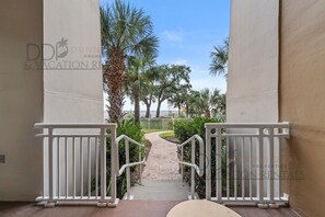 A pathway leading to a gated area with palm trees and a clear sky.