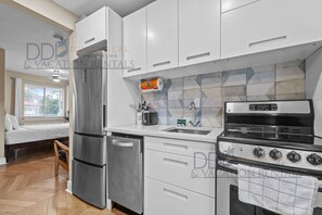 Cocina compacta con refrigerador, estufa y lavamanos.