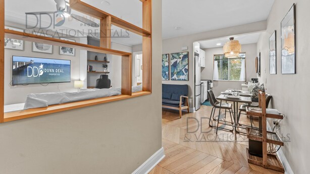 Un interior moderno con comedor, un televisor mostrando 'Dunn Deal Properties' y vistas al exterior.