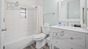 Ein Badezimmer mit Badewanne, Toilette und Waschtisch mit Spiegel.