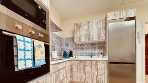 A modern kitchen with a built-in oven, a stainless steel refrigerator, and patterned backsplash tiles.