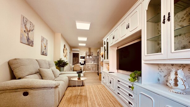A living room with a sofa, TV, cabinets, and artwork.