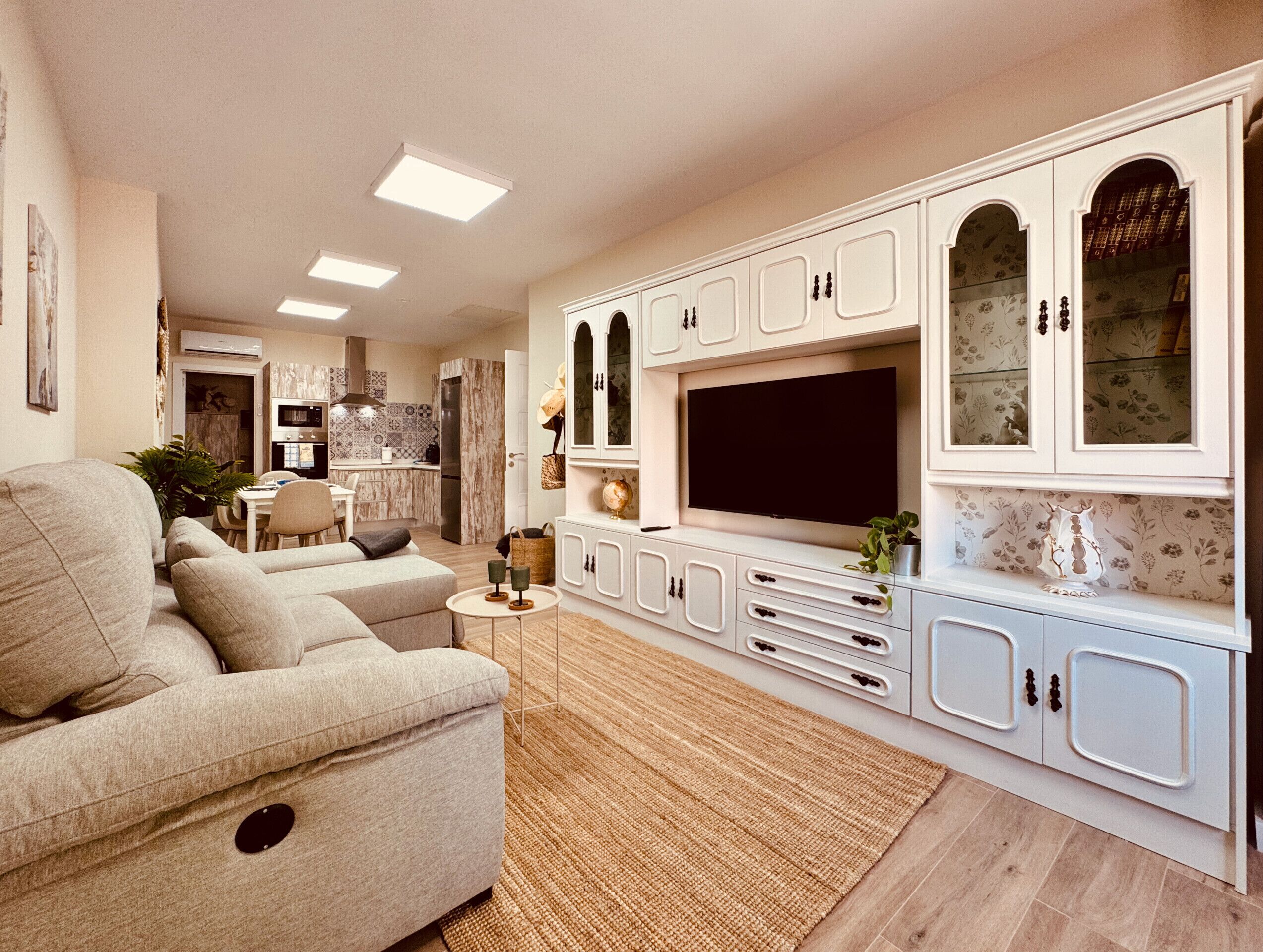 A modern living room with a sofa, TV, and white cabinetry.