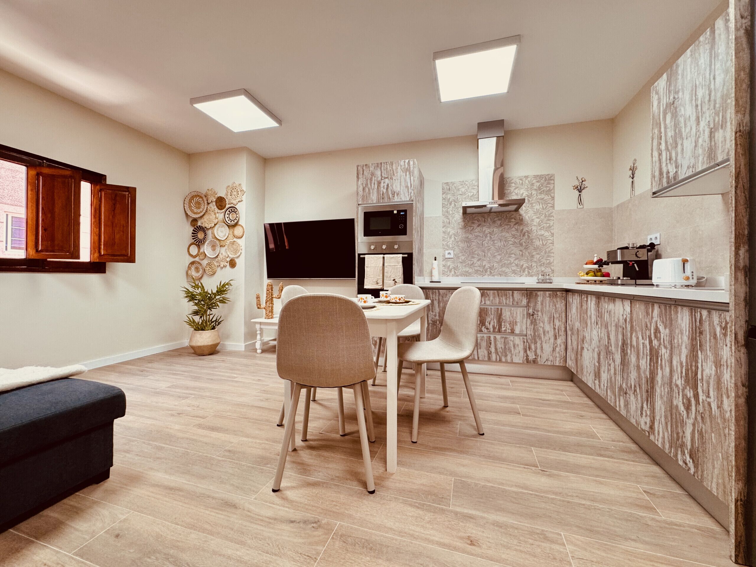A modern kitchen with a dining area, wooden flooring, and a built-in stove.