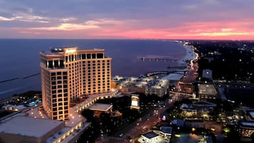 A high-rise hotel with multiple floors, a parking area, and a view of the coastline.