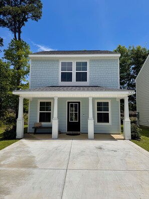 A two-story house with a covered porch, a black front door, and a number '322' on the right side.