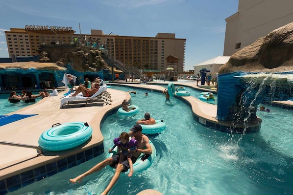 A pool area with multiple water slides and inflatable rings, surrounded by buildings.