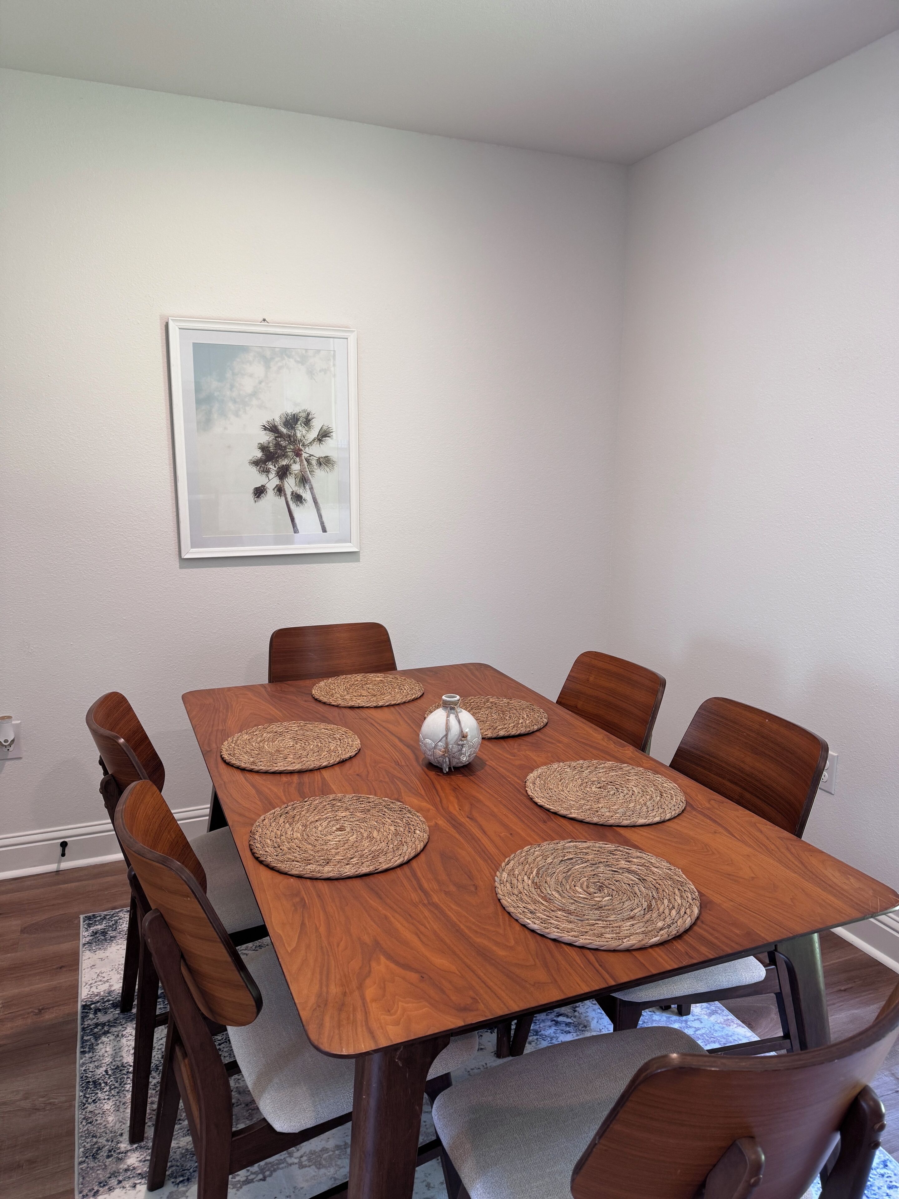 Un comedor con una mesa de madera, seis sillas y un jarrón decorativo.