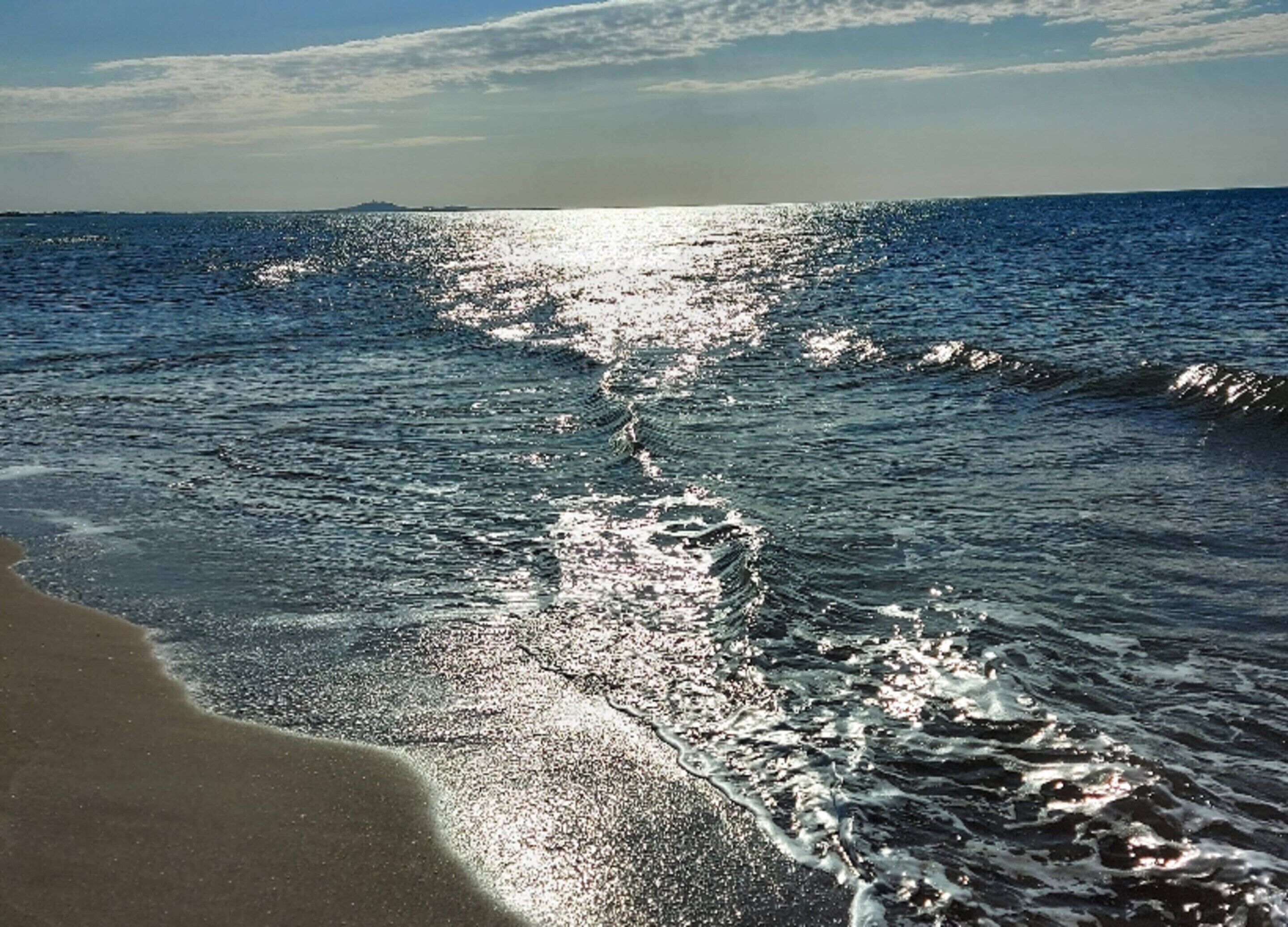 A beach with waves and a clear sky.