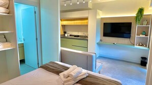 A modern hotel room with a large bed, a TV, and a kitchenette. - Uwin Brooklin NR (São Paulo)