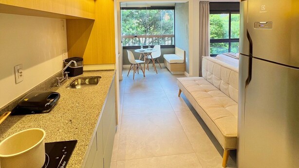 A modern kitchen with a built-in oven, a refrigerator, and a dining area with a table and chairs. - Uwin Brooklin NR (São Paulo)
