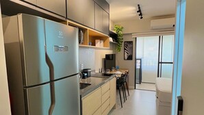 A modern kitchen with a large refrigerator, built-in cabinets, and a dining area with a table and chairs. - Uwin Brooklin NR (São Paulo)