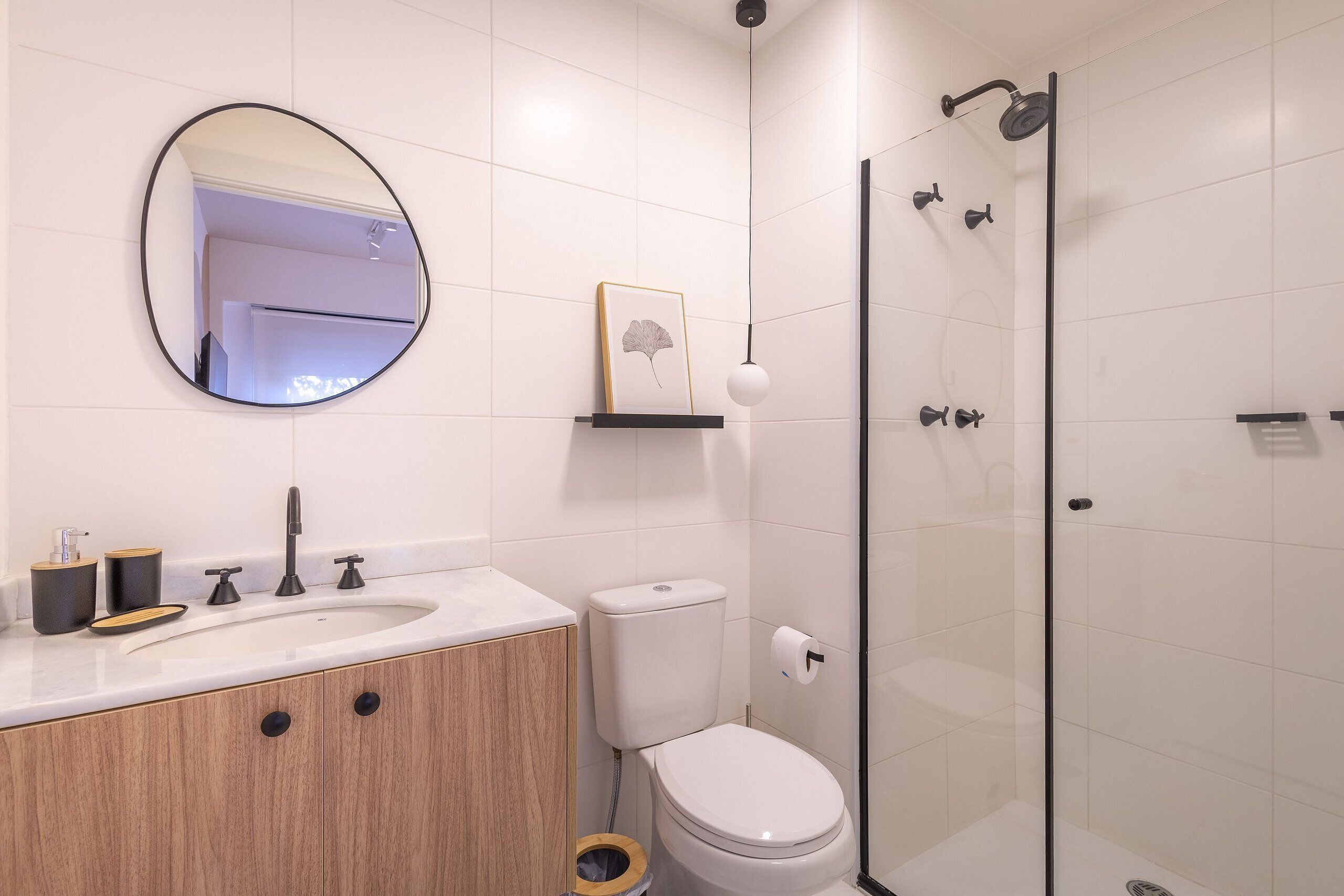 Un baño moderno con lavamanos, inodoro y ducha con mampara de vidrio.
