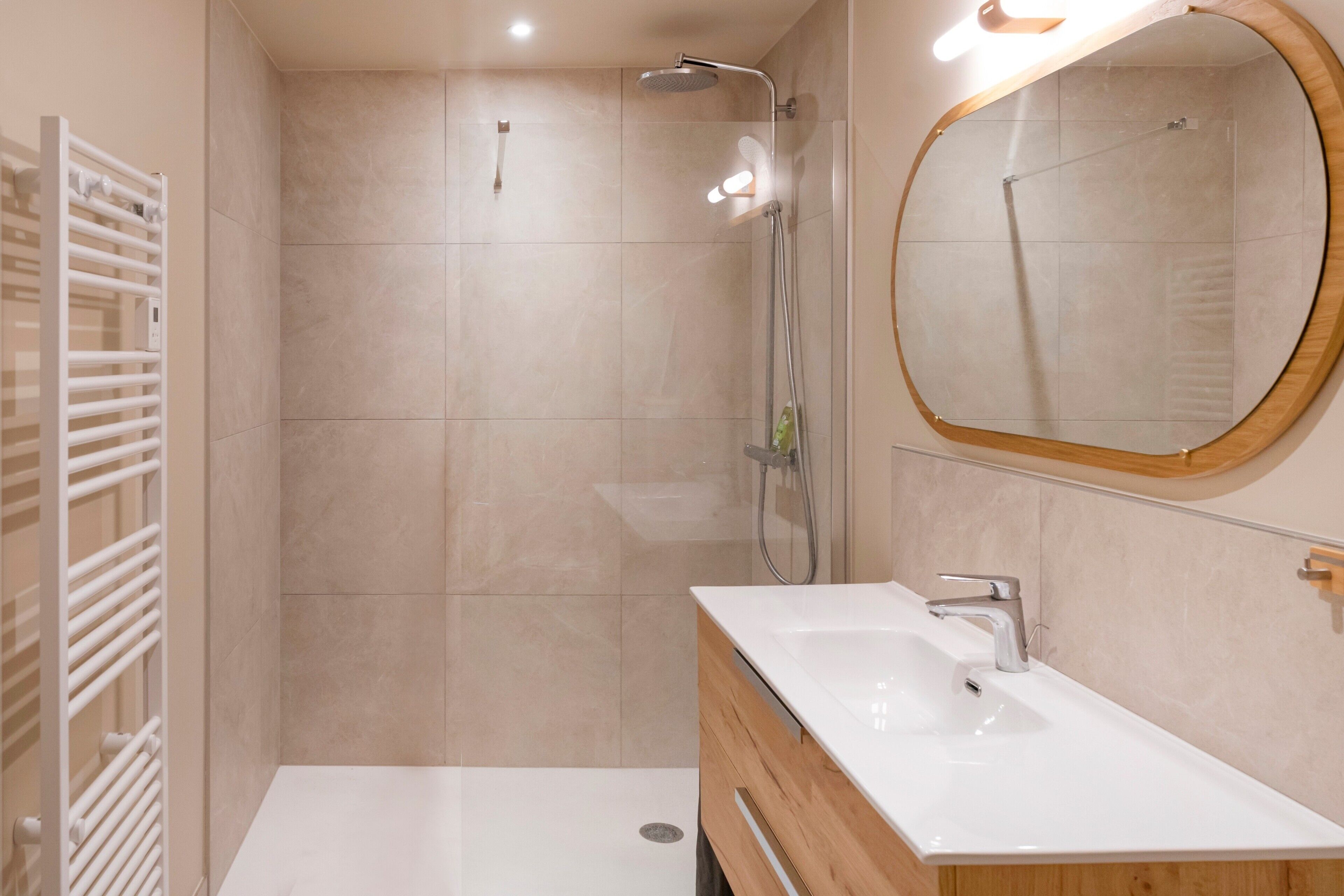 Une salle de bain moderne avec une douche, un lavabo et un miroir.