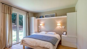 Un dormitorio con cama, mesitas de noche, un armario y una ventana con cortinas.