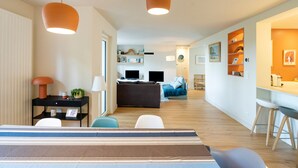 Una sala de estar moderna con un sofá, una mesa de comedor y una zona de cocina al fondo.