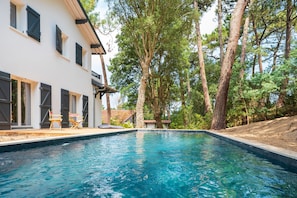 A swimming pool with a white building and trees in the background.
