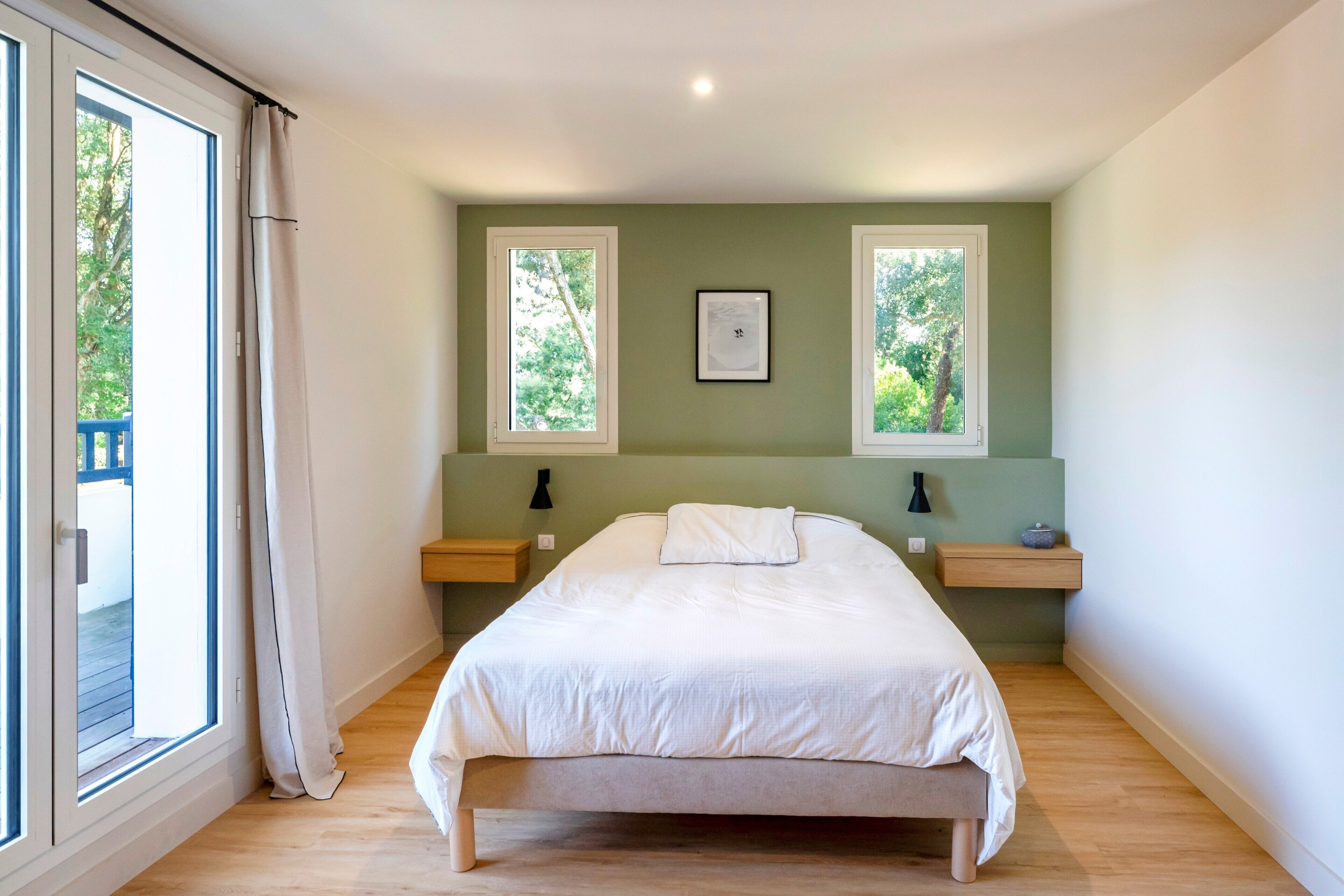 Een slaapkamer met een bed, twee nachtkastjes, een raam en een deur.