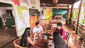Un grupo de personas cenando en una mesa de madera en un ambiente rústico, con el letrero de un hostal local.