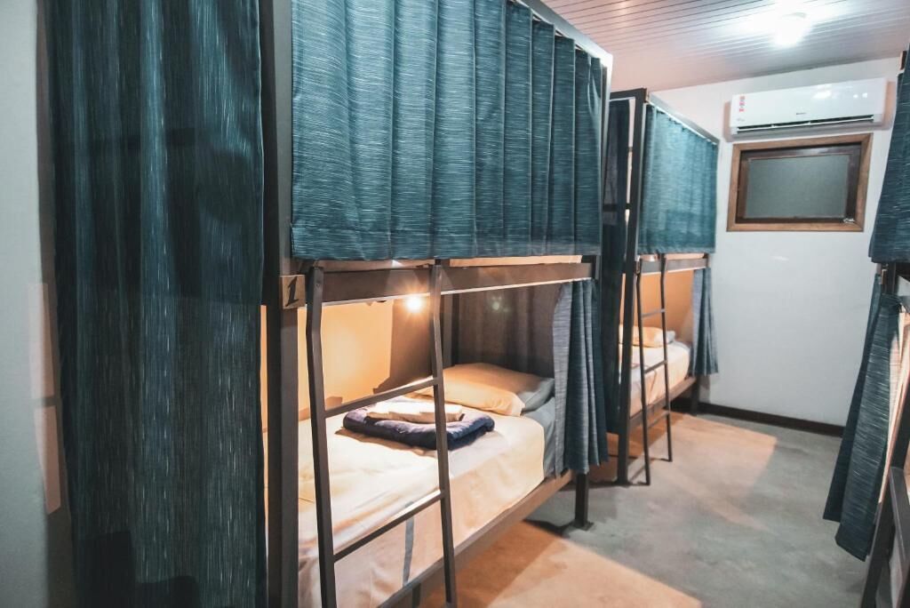 A bunk bed room with a curtain, a window, and an air conditioning unit.