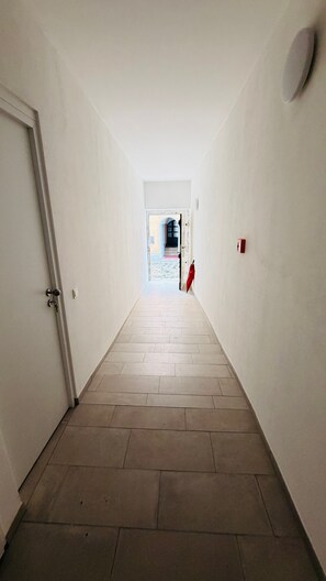 A narrow hallway with a tiled floor leading to a door at the end. - Cozy Corner – Passau (Passau)