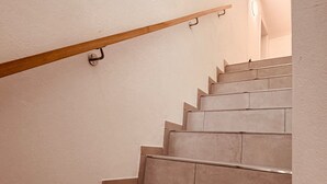 Un escalier avec une rampe en bois et des marches de couleur beige.