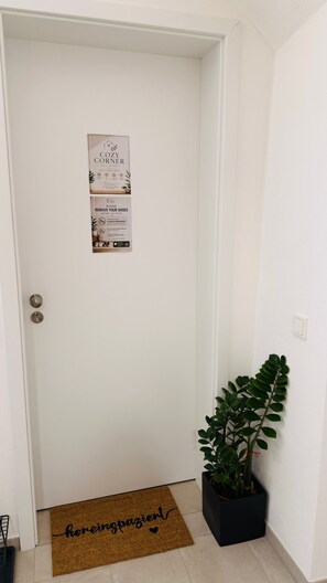 A white door with a sign indicating a cozy corner and a request to remove shoes before entering. - Cozy Corner – Passau (Passau)