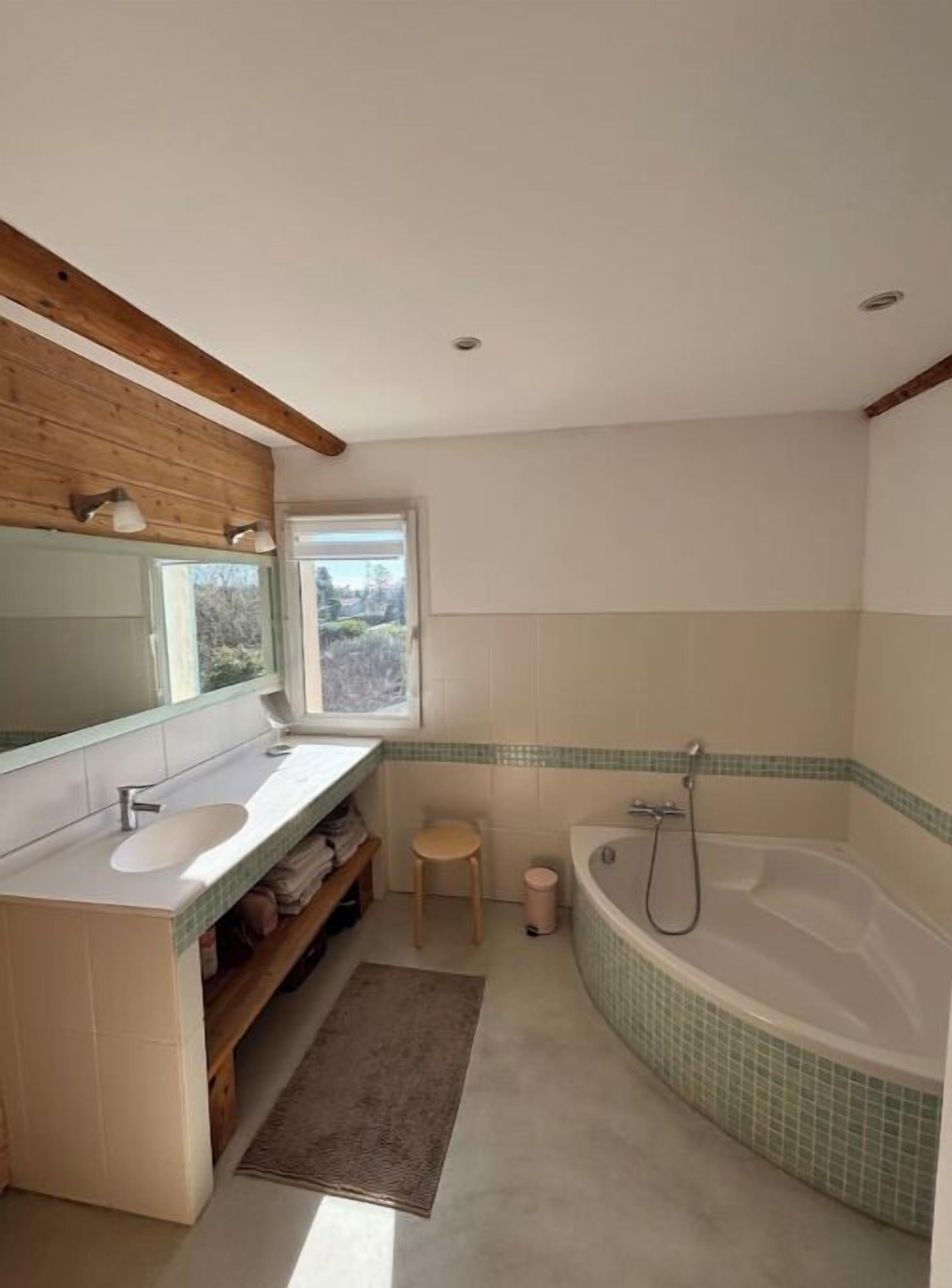 Un bany modern amb sostre de fusta, una banyera gran, un lavabo i una finestra que ofereix vistes a l'exterior.