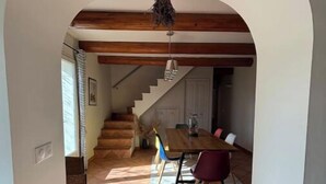 Un coin repas avec une table et des chaises en bois, un escalier menant à une autre pièce et un sol carrelé.