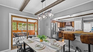 A dining area with a table set for four, a bar area with stools, and a kitchen in the background. - Access to PGA Golf Course- Private Hot Tub-Firepit (Tobyhanna)