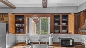 A kitchen with wooden cabinets, a built-in sink, a microwave, and a window with a view of greenery. - Access to PGA Golf Course- Private Hot Tub-Firepit (Tobyhanna)