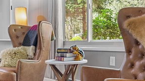 A room with two brown leather armchairs, a small round wooden table, and a bookshelf with books and a stuffed toy. - Access to PGA Golf Course- Private Hot Tub-Firepit (Tobyhanna)