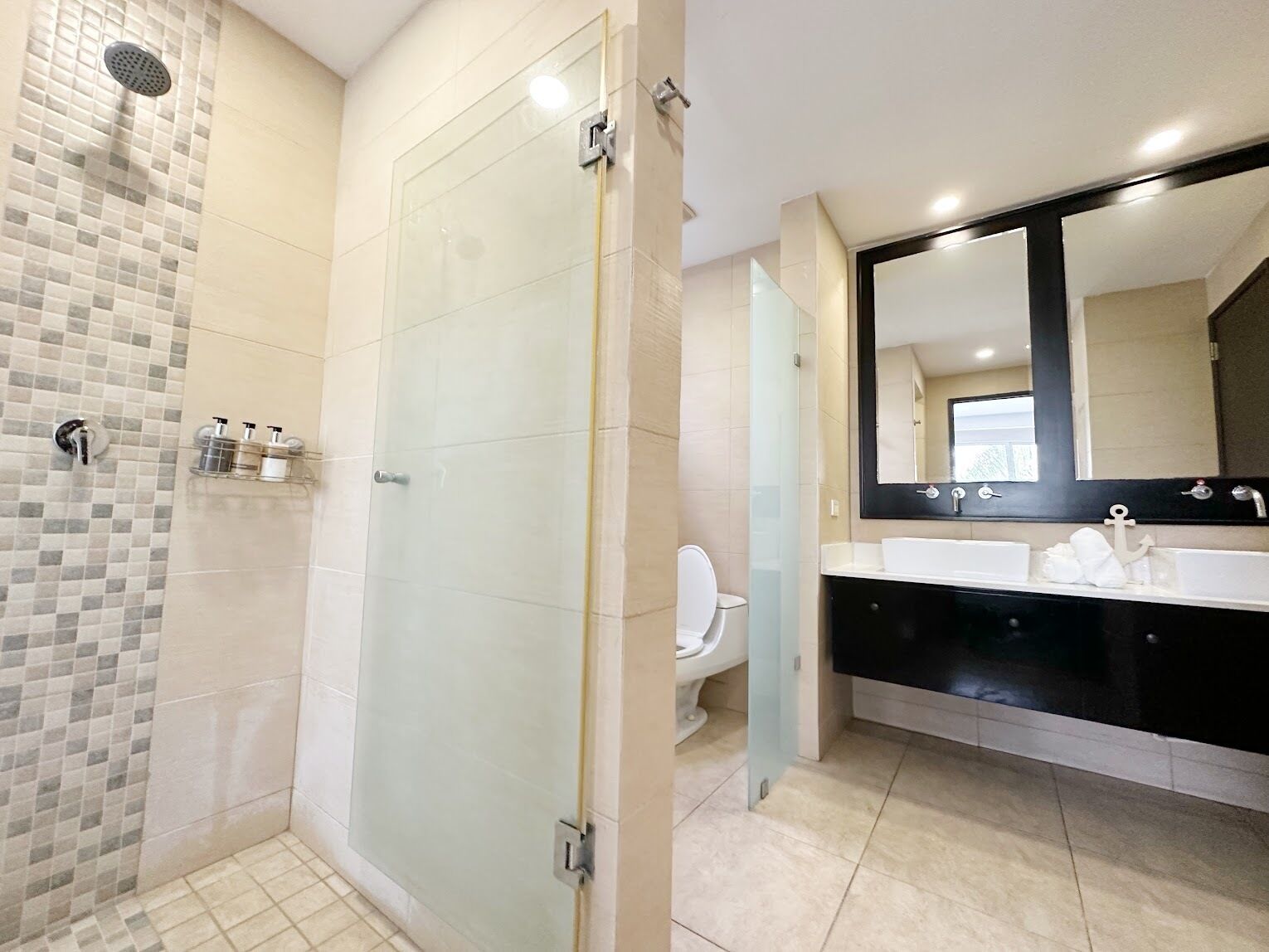 Een moderne badkamer met een douchecabine van glas, een grote spiegel en een wastafel met twee kommen.