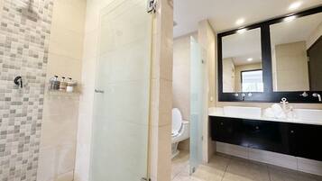 Een moderne badkamer met een douchecabine van glas, een grote spiegel en een wastafel met twee kommen.