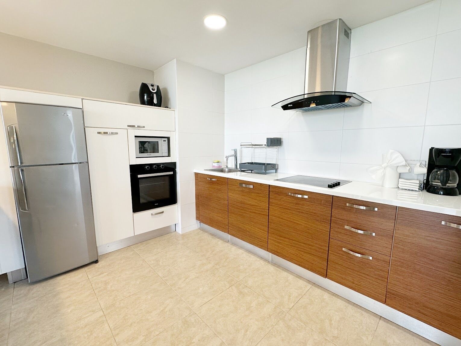 Una cocina moderna equipada con refrigerador, microondas, horno y cafetera.
