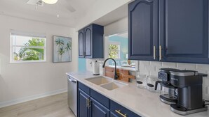 A modern kitchen with dark blue cabinets, a white countertop, and a Keurig coffee maker.