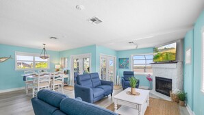 A spacious living room with a fireplace, a dining area, and a view of the outdoors.